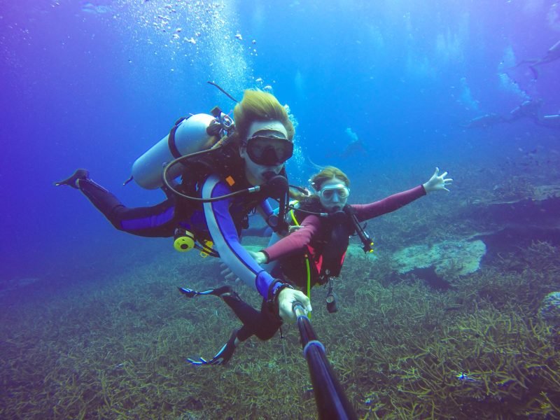 Underwater scuba diving selfie shot with selfie stick. Deep blue sea. Wide angle shot.